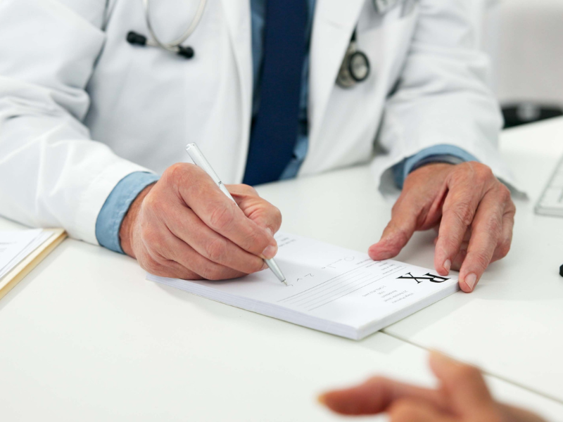 Doctor writing prescription with pen on medical form